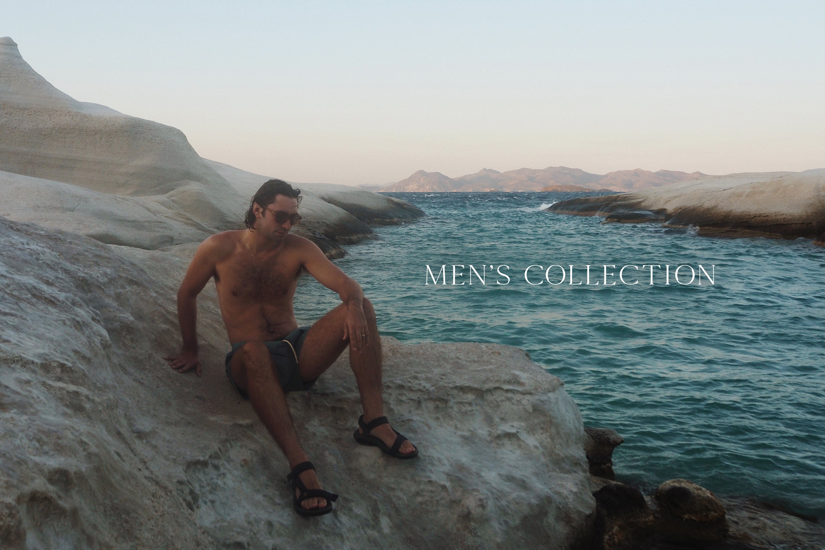 Man sitting on a rock by the ocean with 'Men's Collection' text overlay